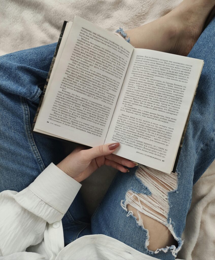 pexels-photo-4170629-4170629 A woman enjoys a relaxing day reading a book while lounging indoors, dressed in casual jeans.